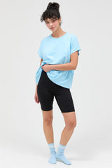 woman wearing a light blue oversized t-shirt and black biker shorts with blue socks