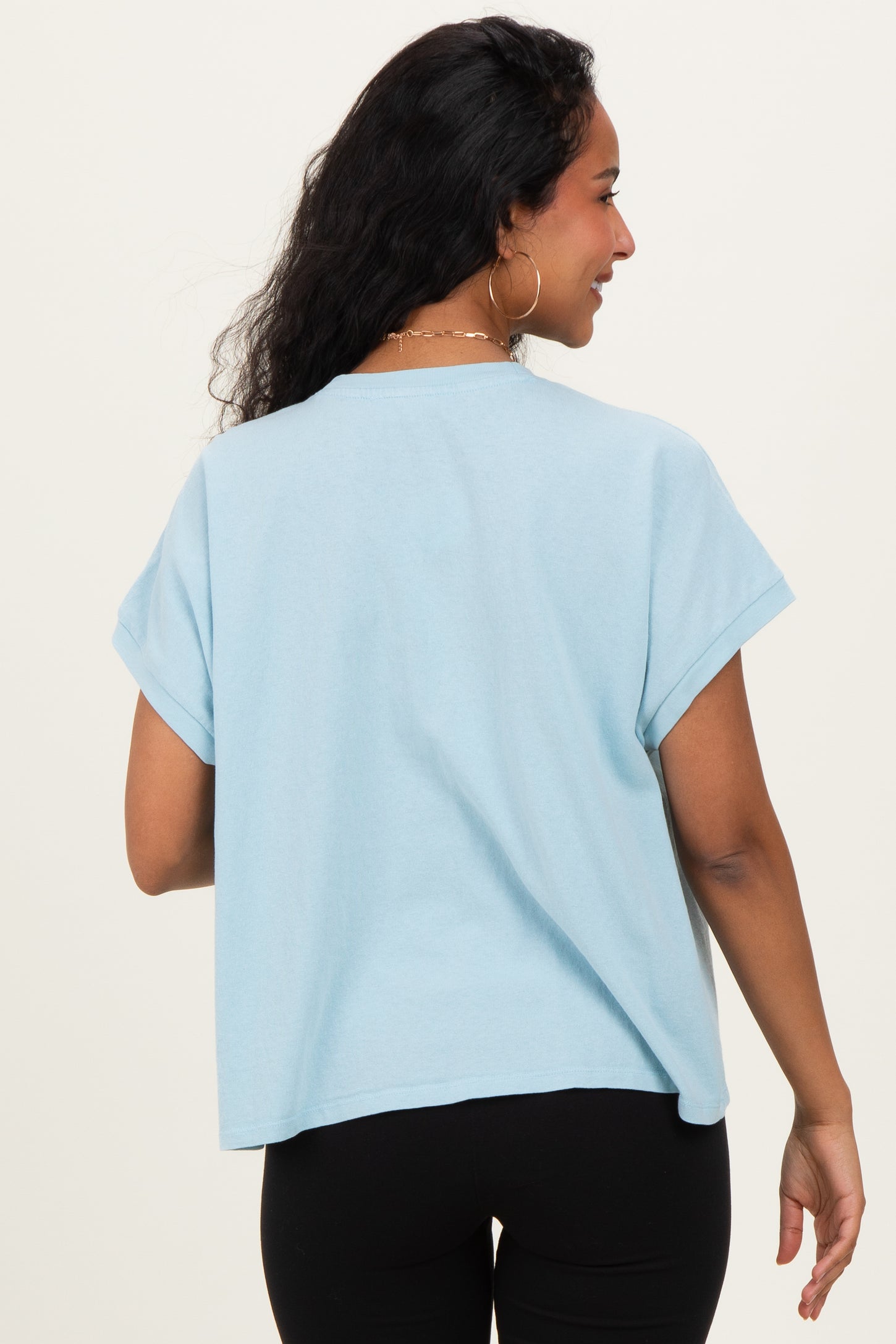 woman wearing a light blue oversized maternity t-shirt with rolled sleeves, showing a relaxed fit and back view