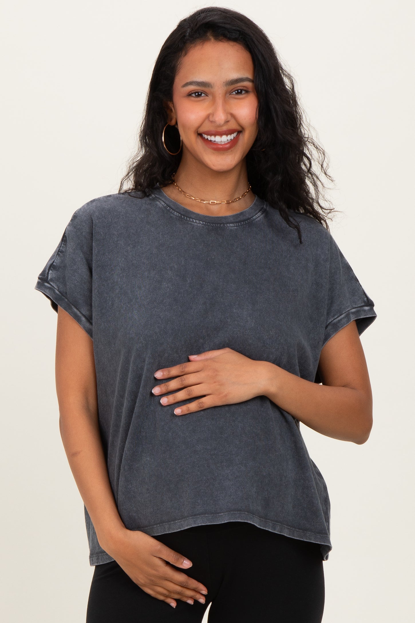 woman wearing a charcoal gray oversized maternity t-shirt and holding her baby bump