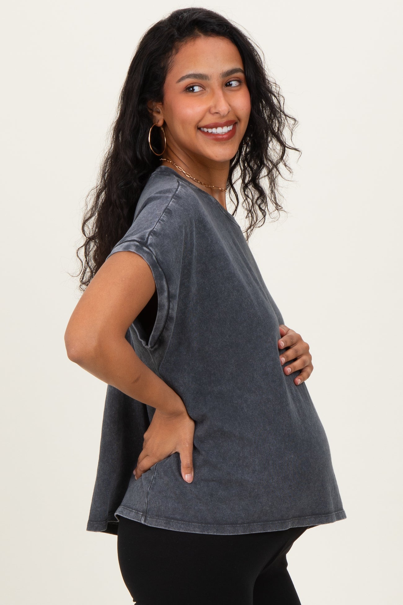woman wearing a dark gray oversized maternity T-shirt and holding her baby bump