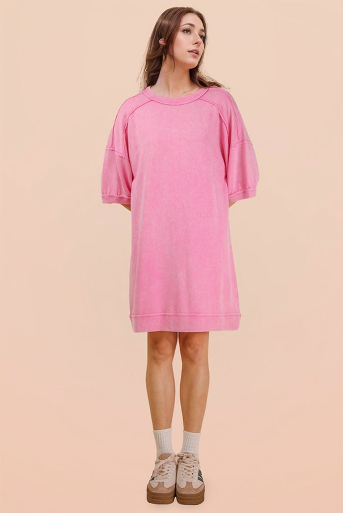 woman wearing a oversized pink sweatshirt dress with short sleeves and a relaxed fit