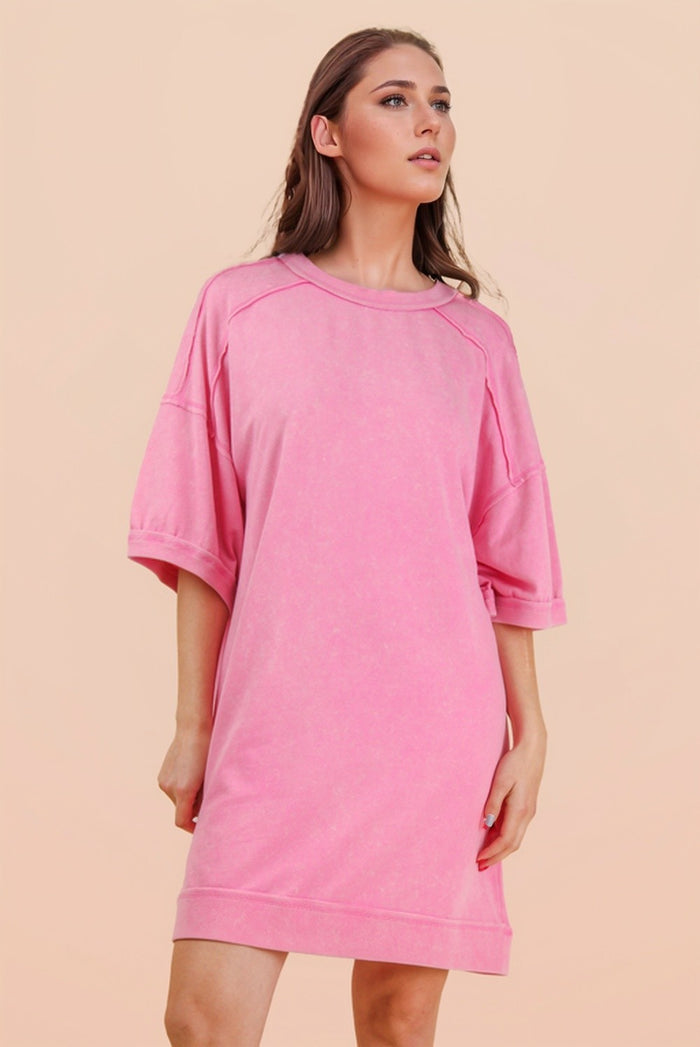 woman wearing a oversized pink sweatshirt dress with short sleeves and a relaxed fit