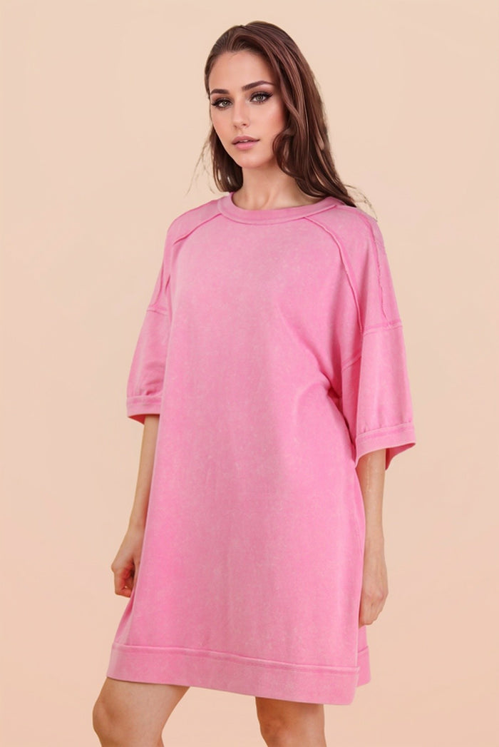 woman wearing a oversized pink sweatshirt dress with short sleeves and a relaxed fit