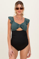 woman wearing a dark green maternity swimsuit with ruffle straps and a tied front, showcasing her baby bump