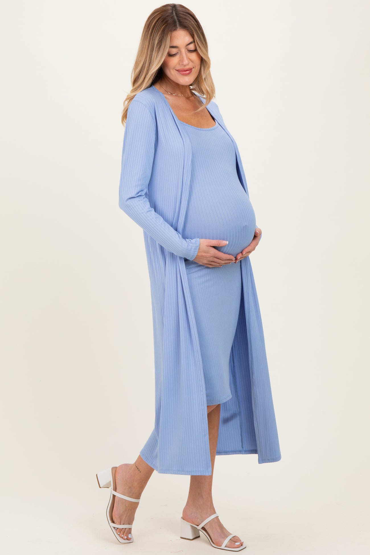 woman wearing a light blue maternity dress and long cardigan, showing off her baby bump