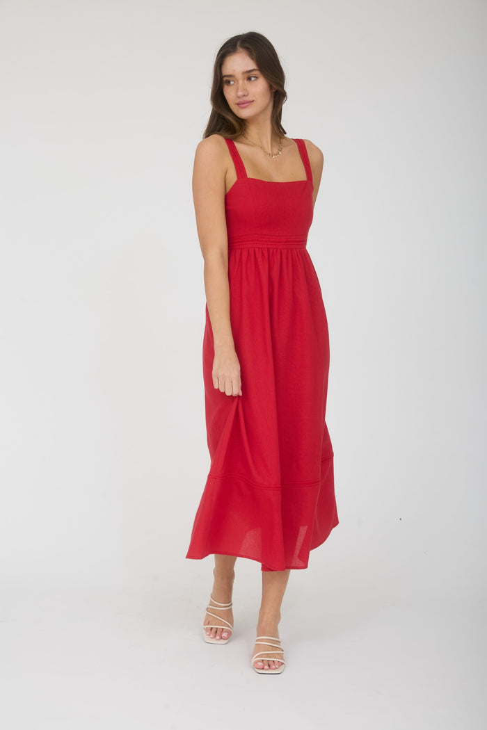 woman wearing a red sleeveless midi dress with a fitted bodice and flared skirt