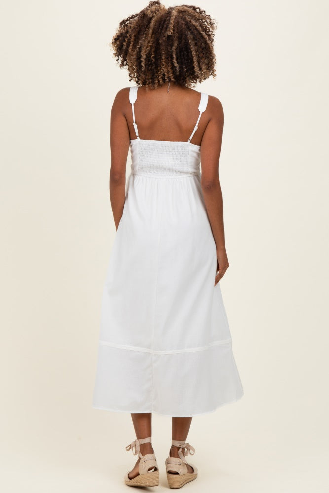 woman wearing a white maternity dress with a smocked bodice and adjustable straps, showcasing a relaxed fit