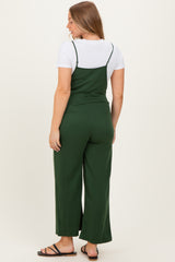 woman wearing a dark green maternity jumpsuit with wide legs and a t-shirt underneath, viewed from the back