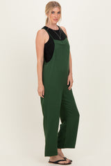 woman wearing a green sleeveless jumpsuit with wide legs and a black tank top underneath