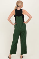 woman wearing a black tank top and green wide-leg jumpsuit, showing the back view with adjustable straps