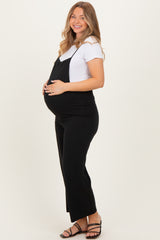 woman wearing a black maternity jumpsuit over a white tee with a visible baby bump