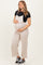 woman wearing a beige maternity jumpsuit and holding her baby bump, paired with a black t-shirt and sneakers