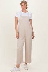 woman wearing a beige wide-leg jumpsuit over a white t-shirt with white sneakers