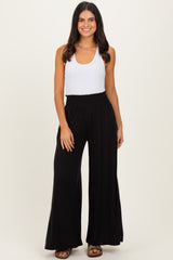woman wearing a white tank top and black wide-leg pants with a smocked waistband