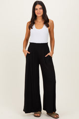 woman wearing a white tank top and black wide-leg pants with a smocked waistband and pockets