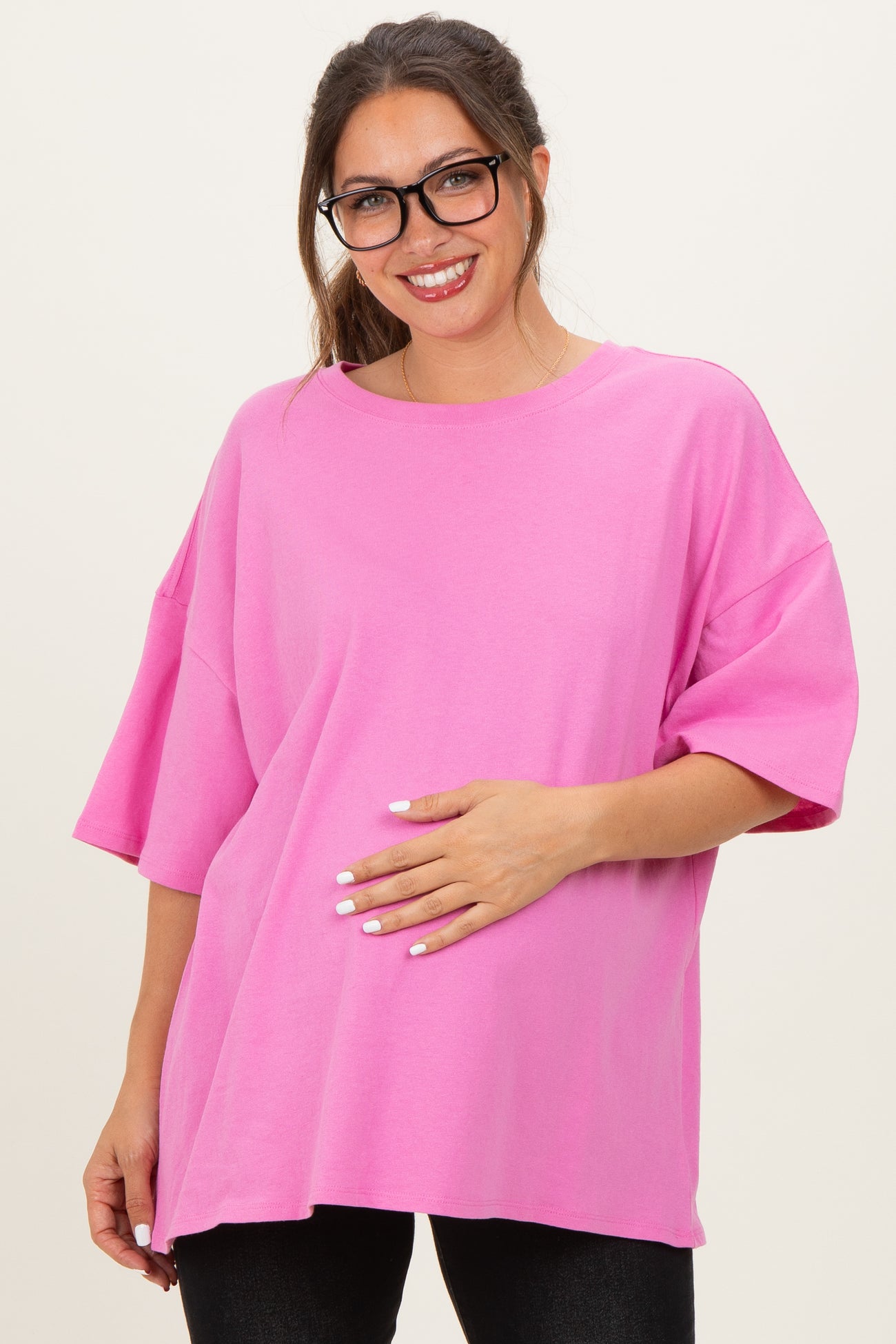 woman wearing a bright pink oversized maternity t-shirt and holding her baby bump