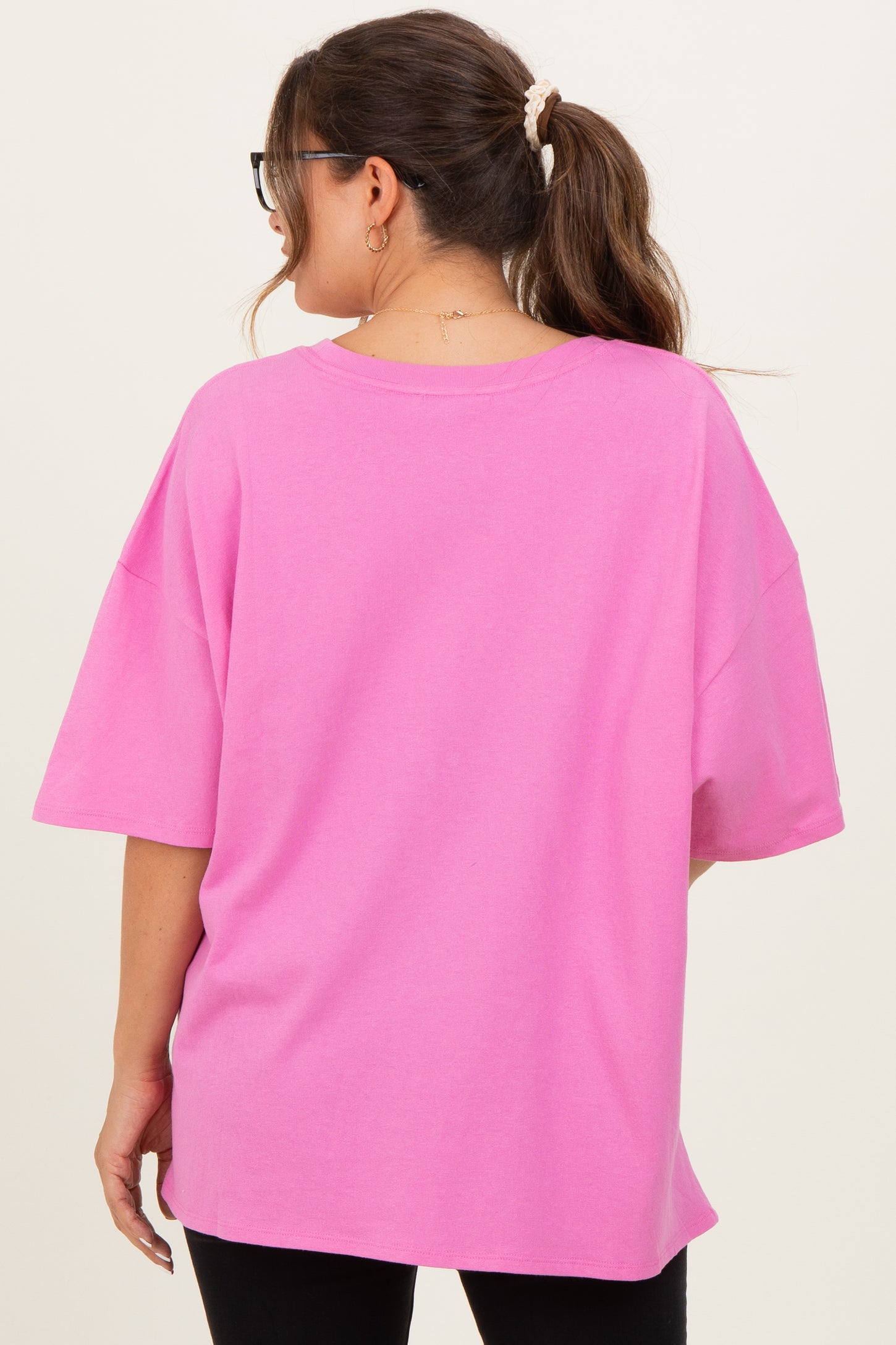 woman wearing a loose-fitting bright pink maternity top, shown from the back, with casual style and short sleeves