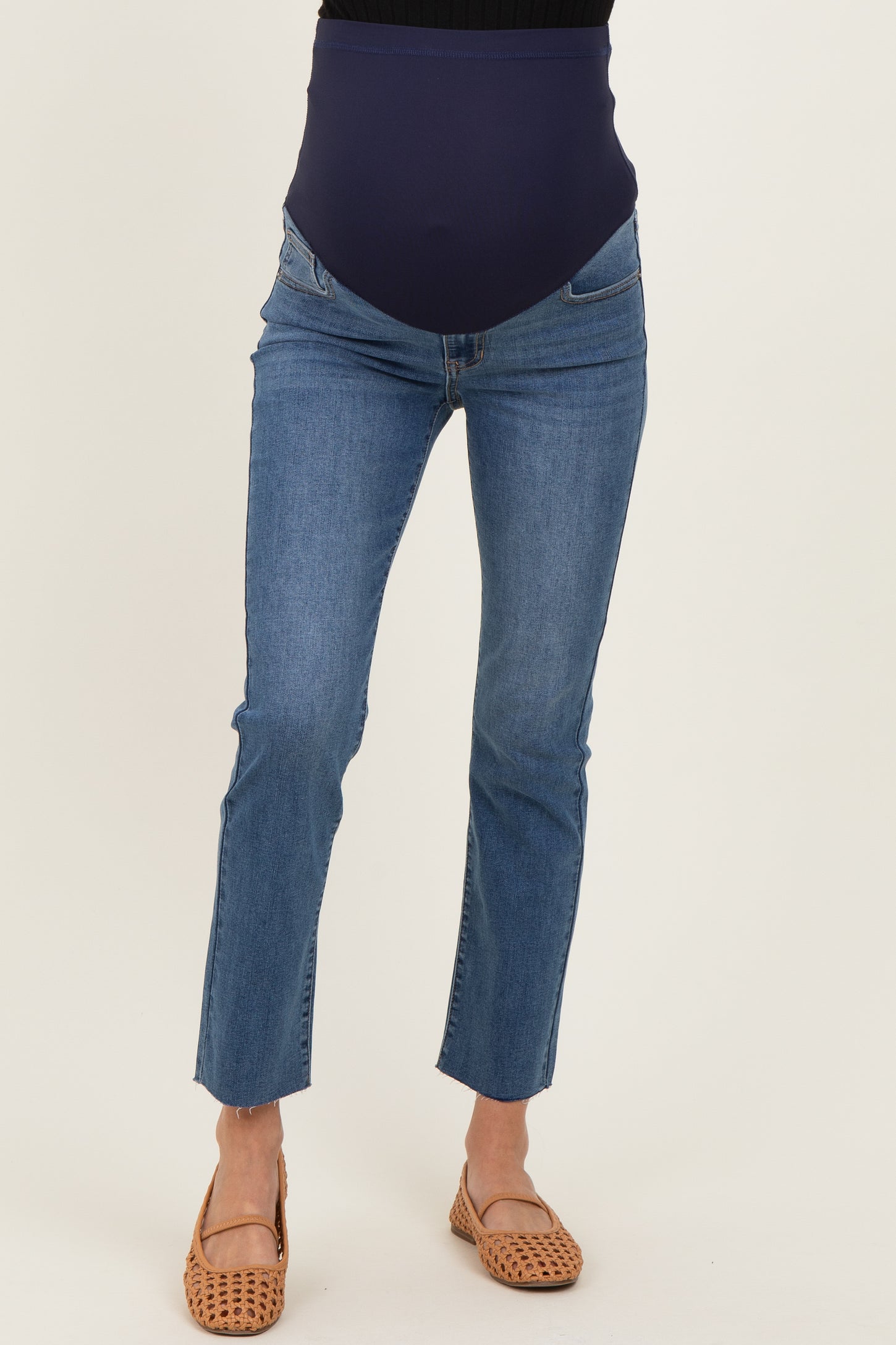 woman wearing a pair of blue denim maternity jeans with a stretchy navy waistband and light brown sandals
