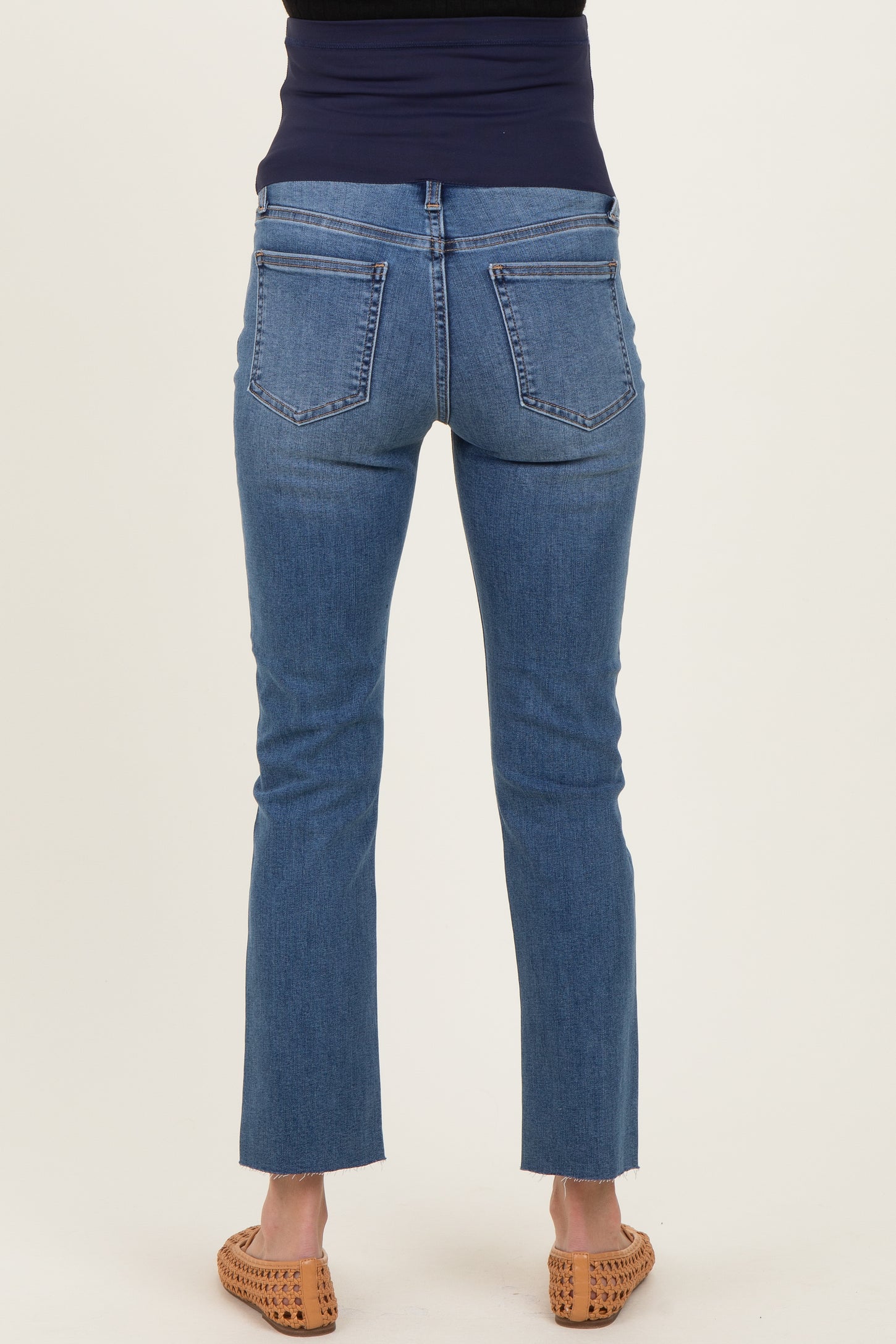 woman wearing a pair of blue maternity jeans with a straight leg and frayed hem, viewed from the back.