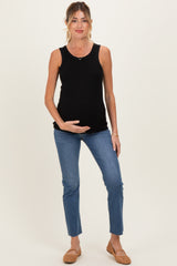 woman wearing a black ribbed maternity tank top and blue jeans, holding her baby bump