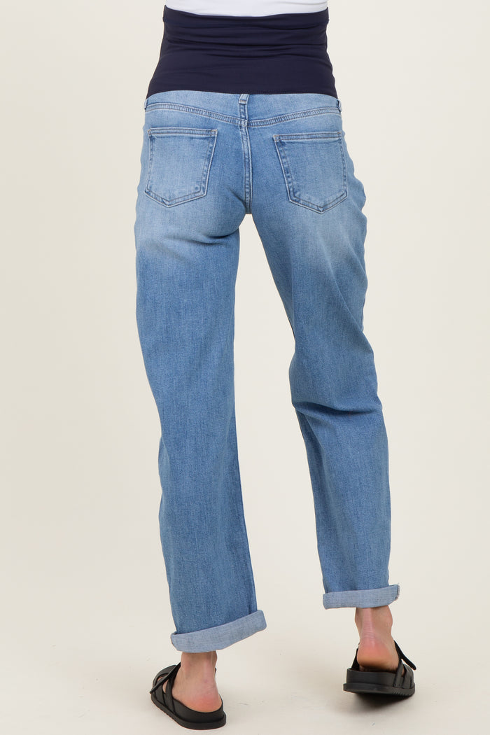 woman wearing light blue maternity jeans with a dark waistband, seen from the back, with a relaxed fit and rolled cuffs