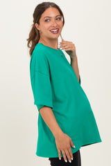 woman wearing a bright green oversized maternity top and showing off her baby bump