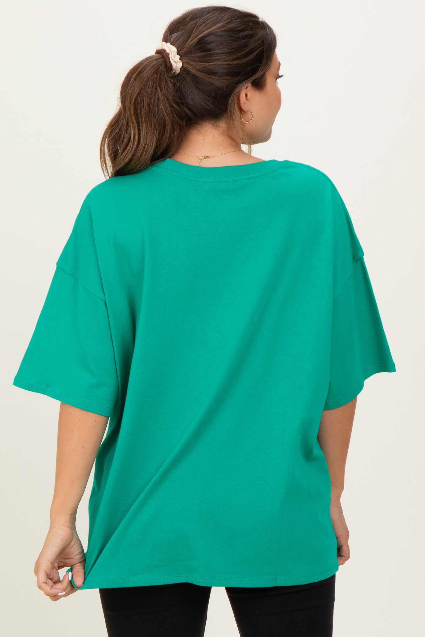 woman wearing a loose-fitting bright green maternity t-shirt, seen from the back