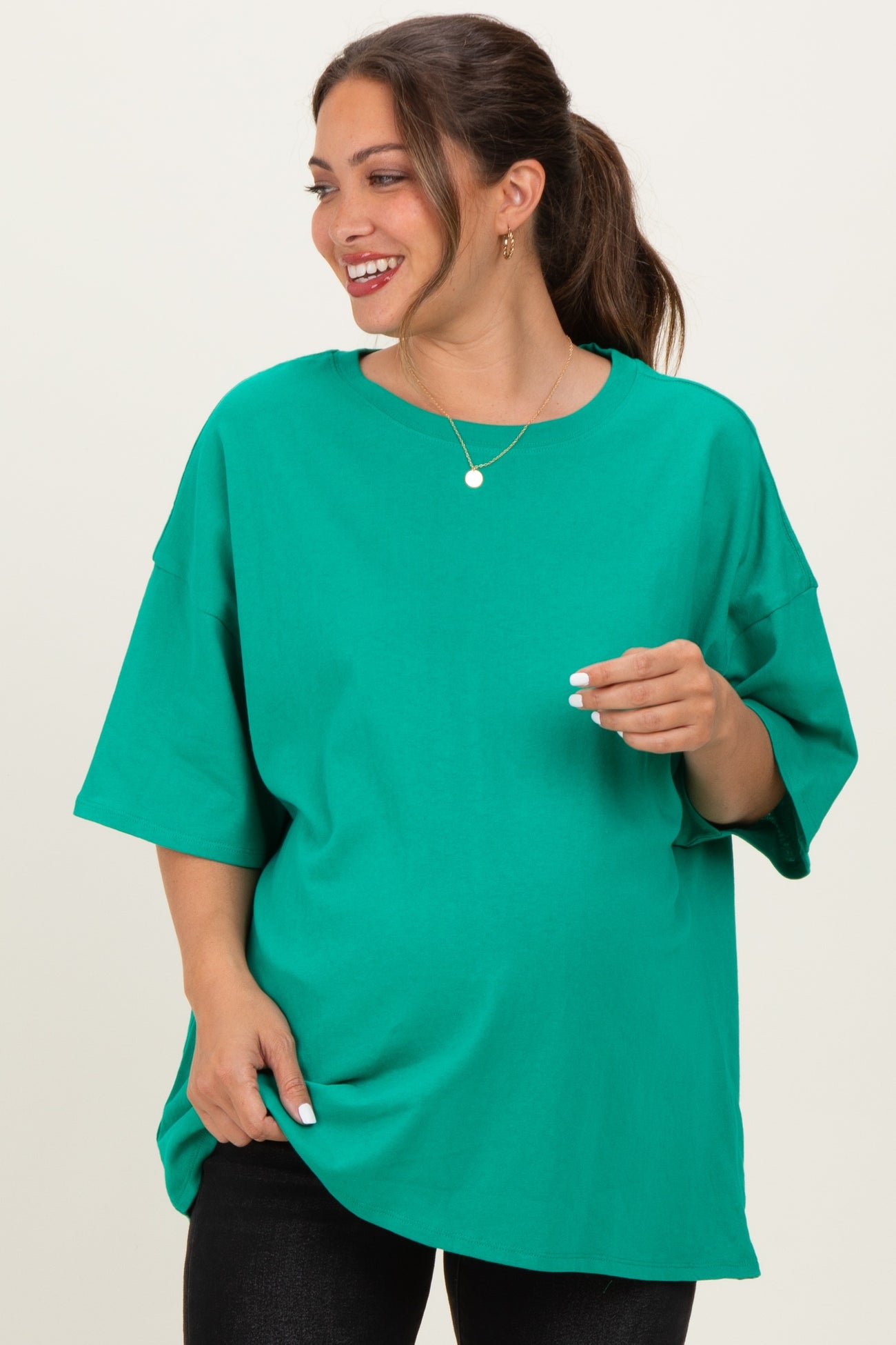woman wearing a bright green oversized maternity t-shirt and showing her baby bump