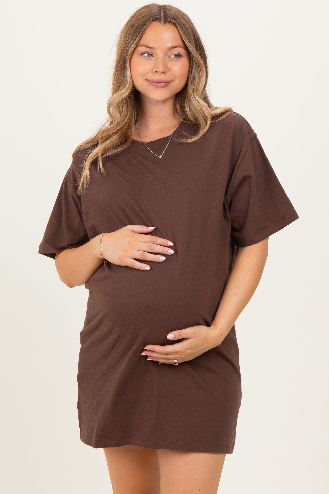 woman wearing a chocolate brown short sleeve maternity dress and holding her baby bump