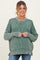 woman wearing a green striped oversized maternity sweater with a relaxed fit and ribbed details