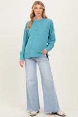 woman wearing a teal maternity sweater with long sleeves and relaxed fit paired with light wash flared jeans