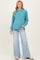 woman wearing a teal maternity sweater with long sleeves and relaxed fit paired with light wash flared jeans