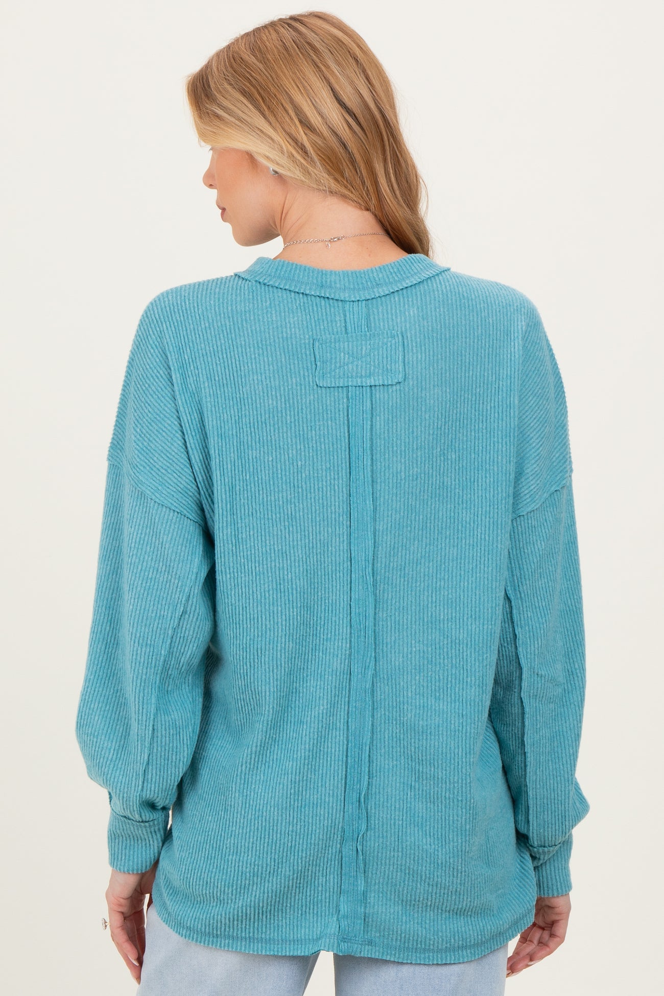 woman wearing a turquoise ribbed maternity top with long sleeves and a relaxed fit, seen from the back