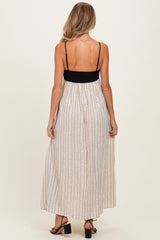 woman wearing a back view of a black and white striped maternity maxi dress with adjustable spaghetti straps
