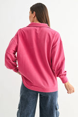 woman wearing a pink oversized long sleeve shirt, seen from the back, styled with denim cargo pants