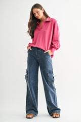 woman wearing a pink long sleeve oversized polo shirt and dark blue wide-leg cargo pants with side pockets