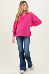 woman wearing a pink long sleeve maternity top and flared jeans, showing her baby bump