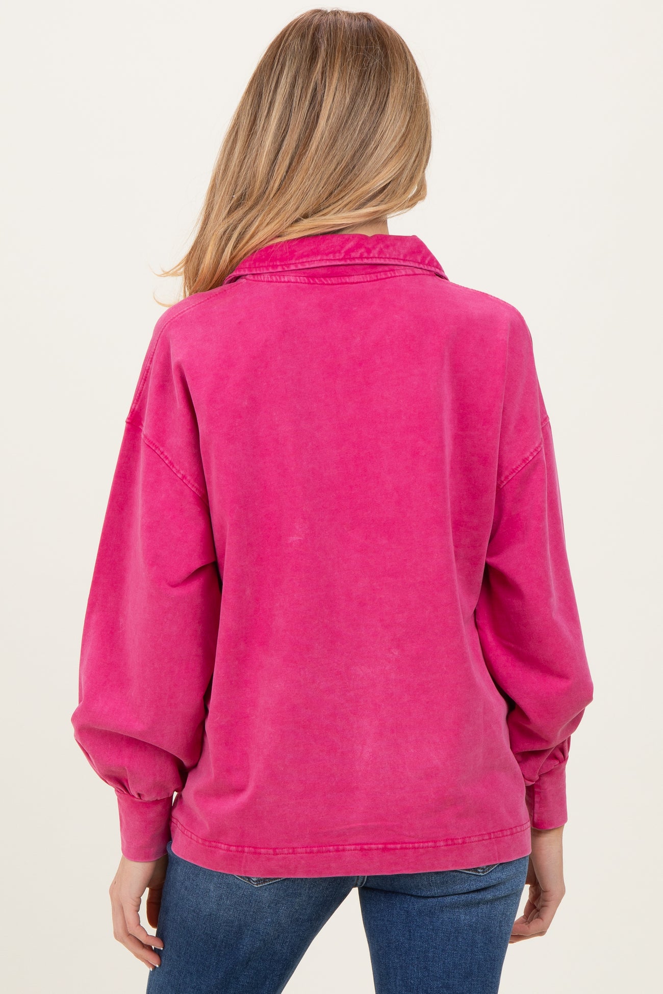 woman wearing a pink oversized maternity sweatshirt with a collared neckline and balloon sleeves, viewed from the back