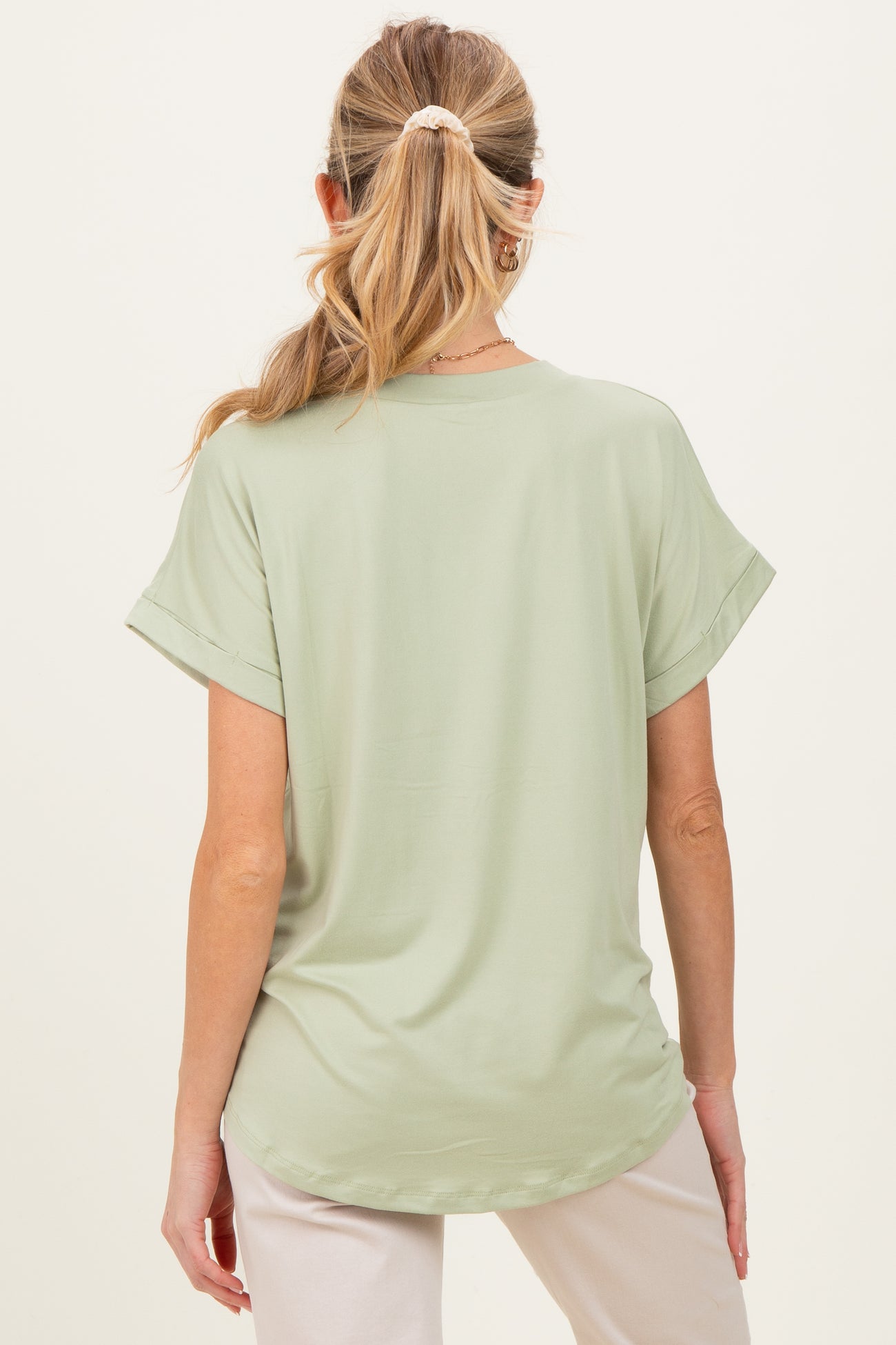 woman wearing a light green short sleeve maternity top, seen from the back