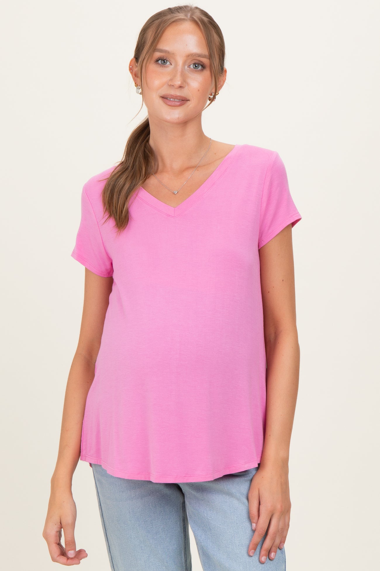 woman wearing a pink v-neck maternity top and showing her baby bump