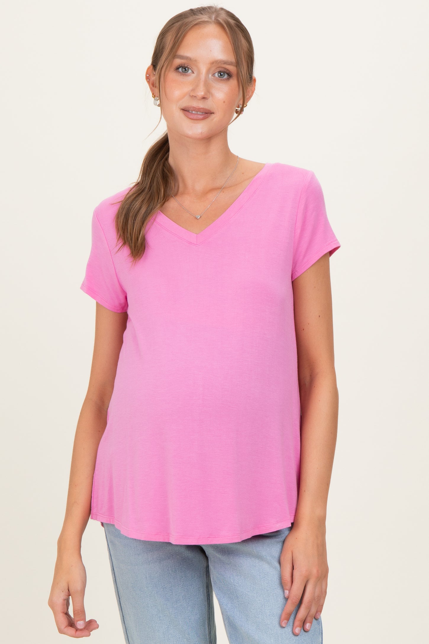 woman wearing a pink v-neck maternity top and showing her baby bump
