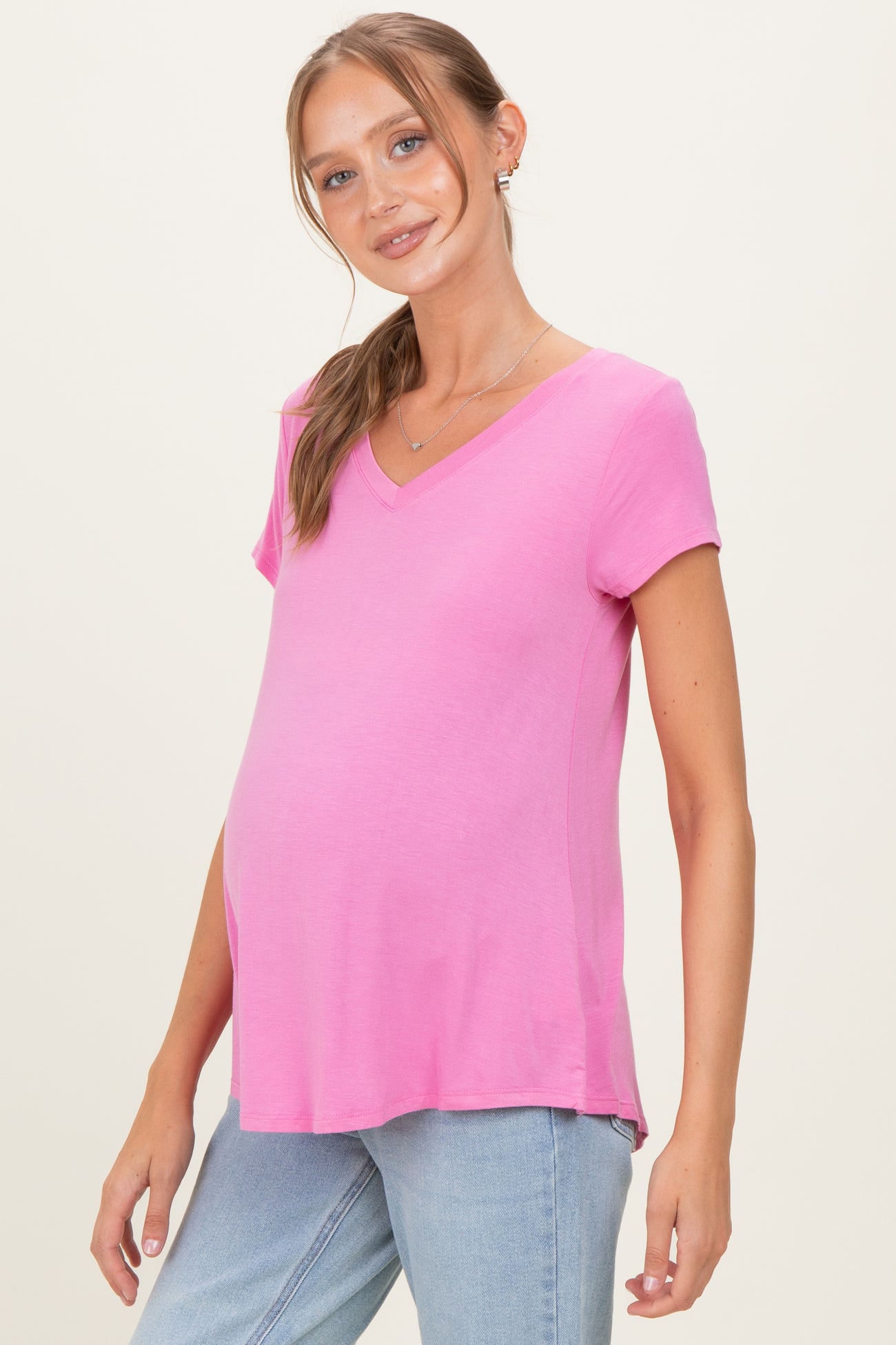 woman wearing a pink short sleeve maternity top with a v-neck and a visible baby bump