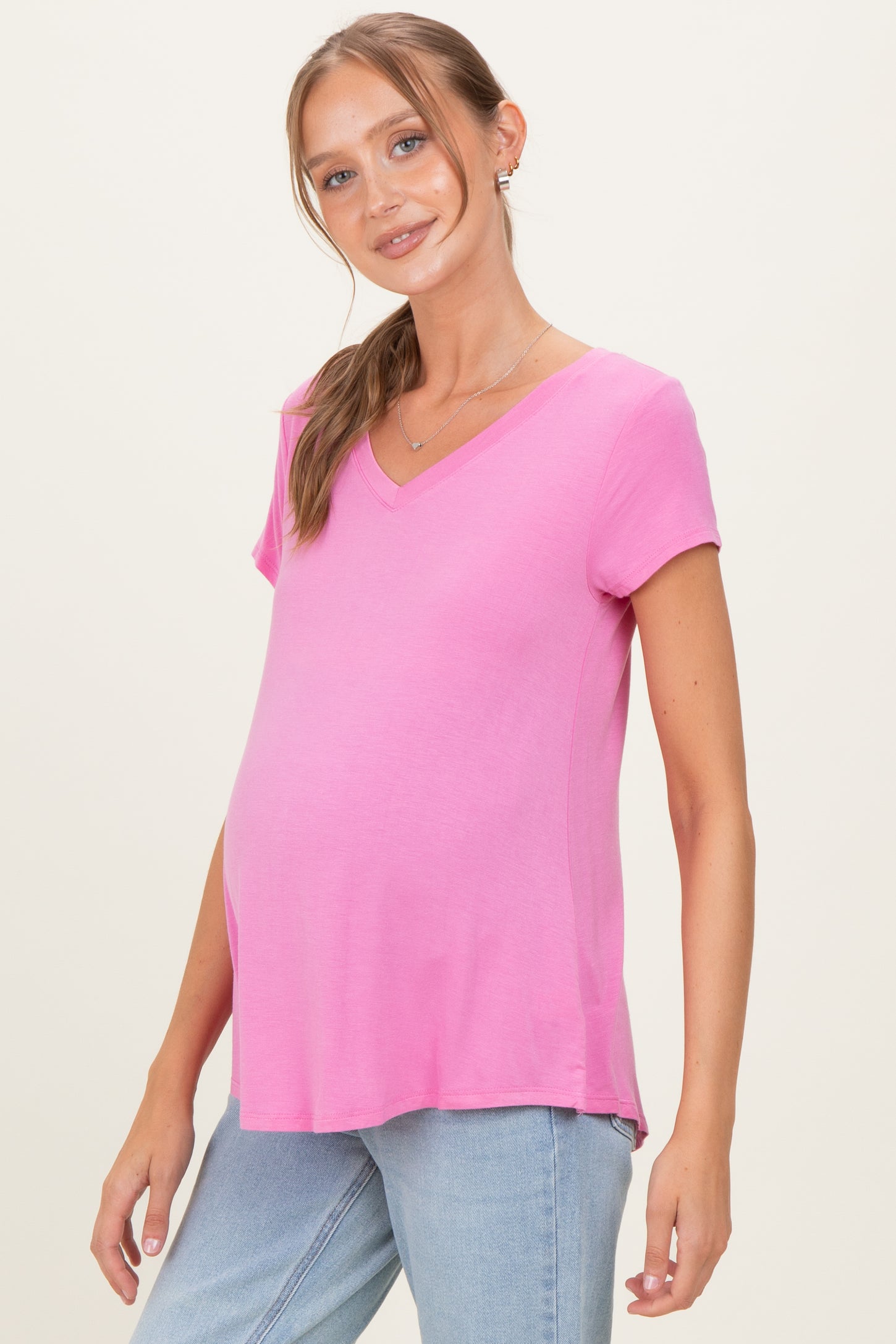 woman wearing a pink short sleeve maternity top with a v-neck and a visible baby bump