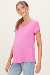 woman wearing a pink short sleeve maternity top with a v-neck and a visible baby bump