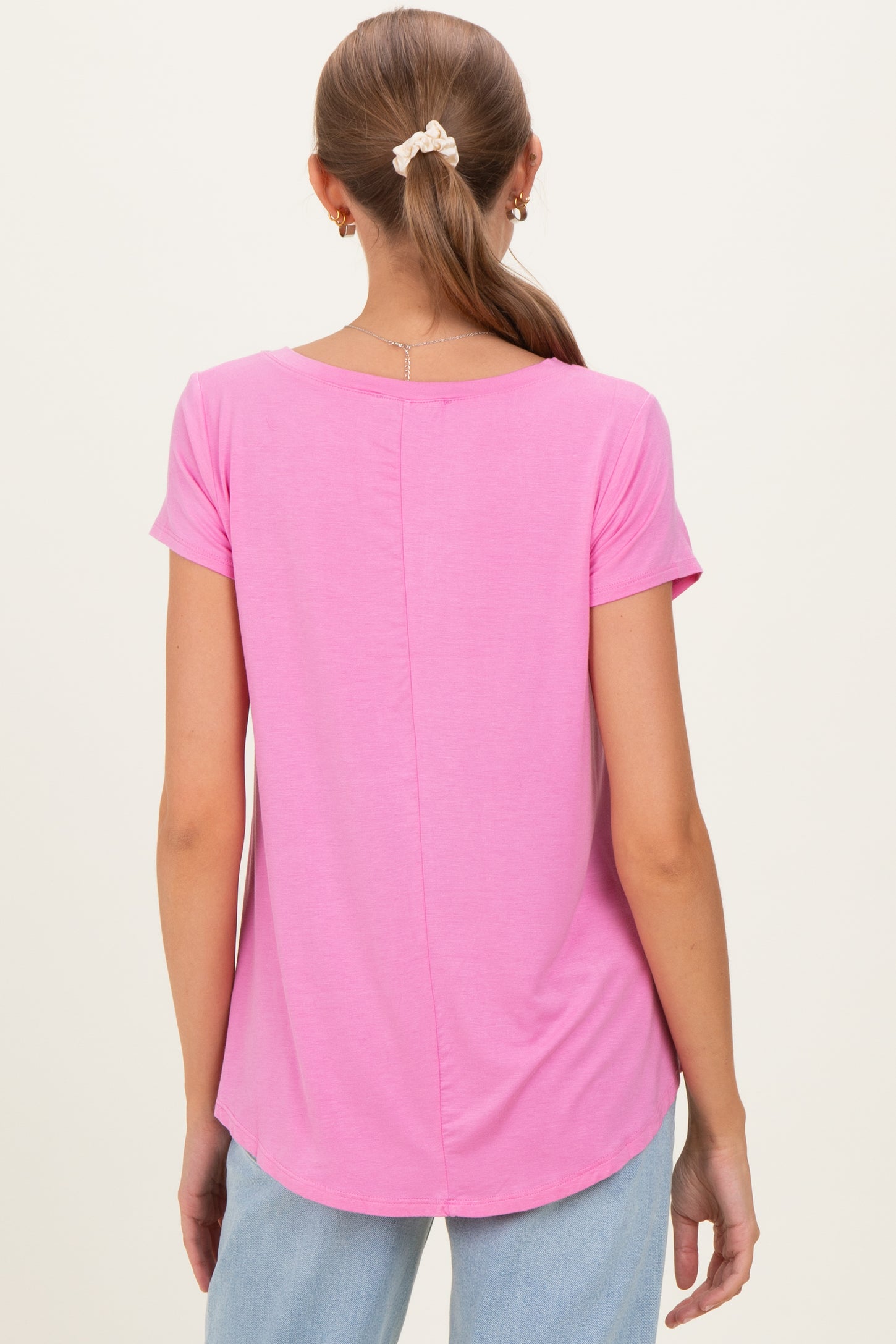 woman wearing a pink maternity t-shirt with short sleeves and a rounded hem, view from the back