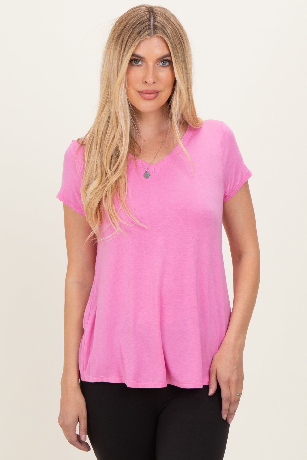 woman wearing a vibrant pink short sleeve top with a v-neckline and relaxed fit