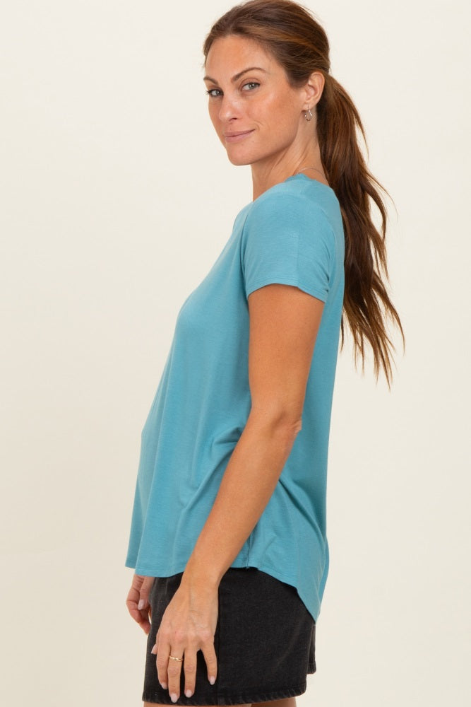 woman wearing a teal short sleeve top with a relaxed fit and side slit, paired with black denim shorts