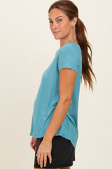 woman wearing a teal short sleeve top with a relaxed fit and side slit, paired with black denim shorts