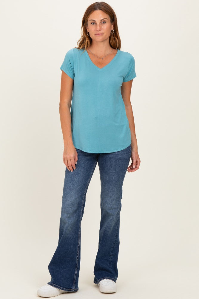 woman wearing a teal v-neck t-shirt and flared jeans with white sneakers