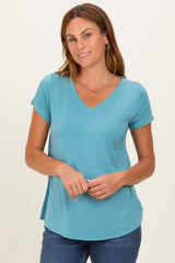 woman wearing a teal short sleeve v-neck top with a relaxed fit, standing and smiling